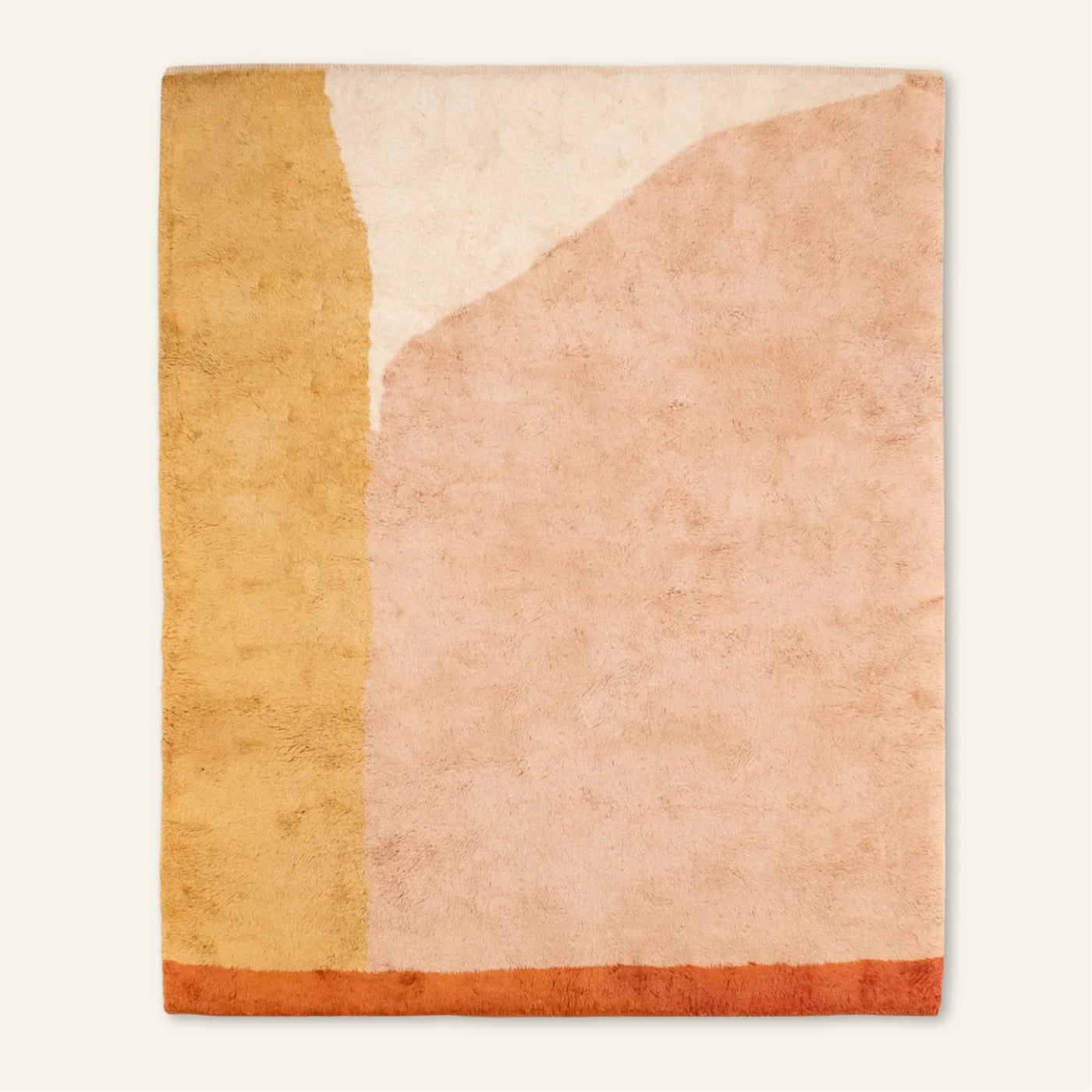 Vue entière du tapis aux grands aplats pêche, ocre et crème et à la bande orange sur un côté.